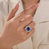 Blue cushion cut engagement ring worn on hand